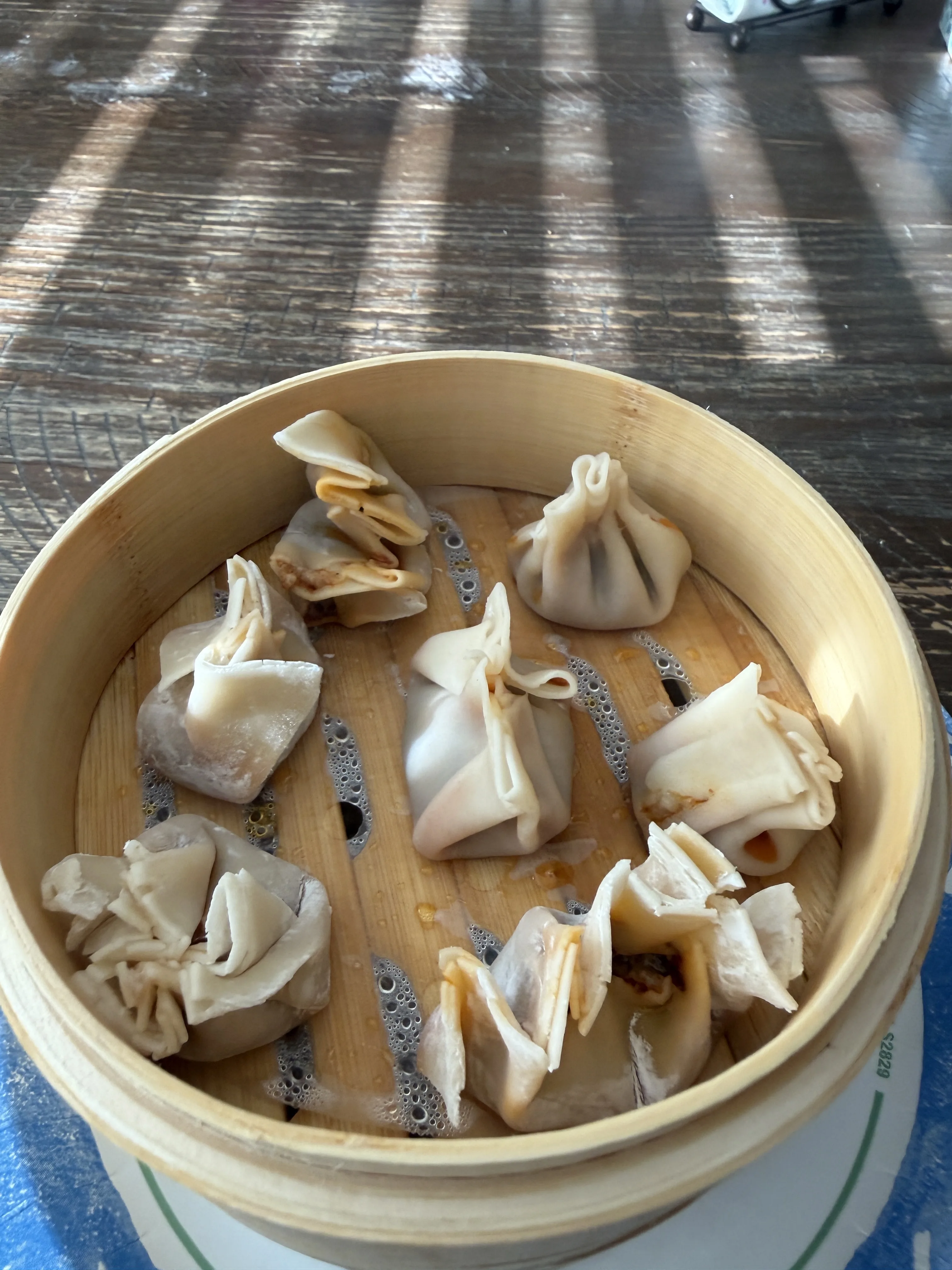 Hand-folded Chinese steamed pork and chive dumplings in a bamboo steamer basket
