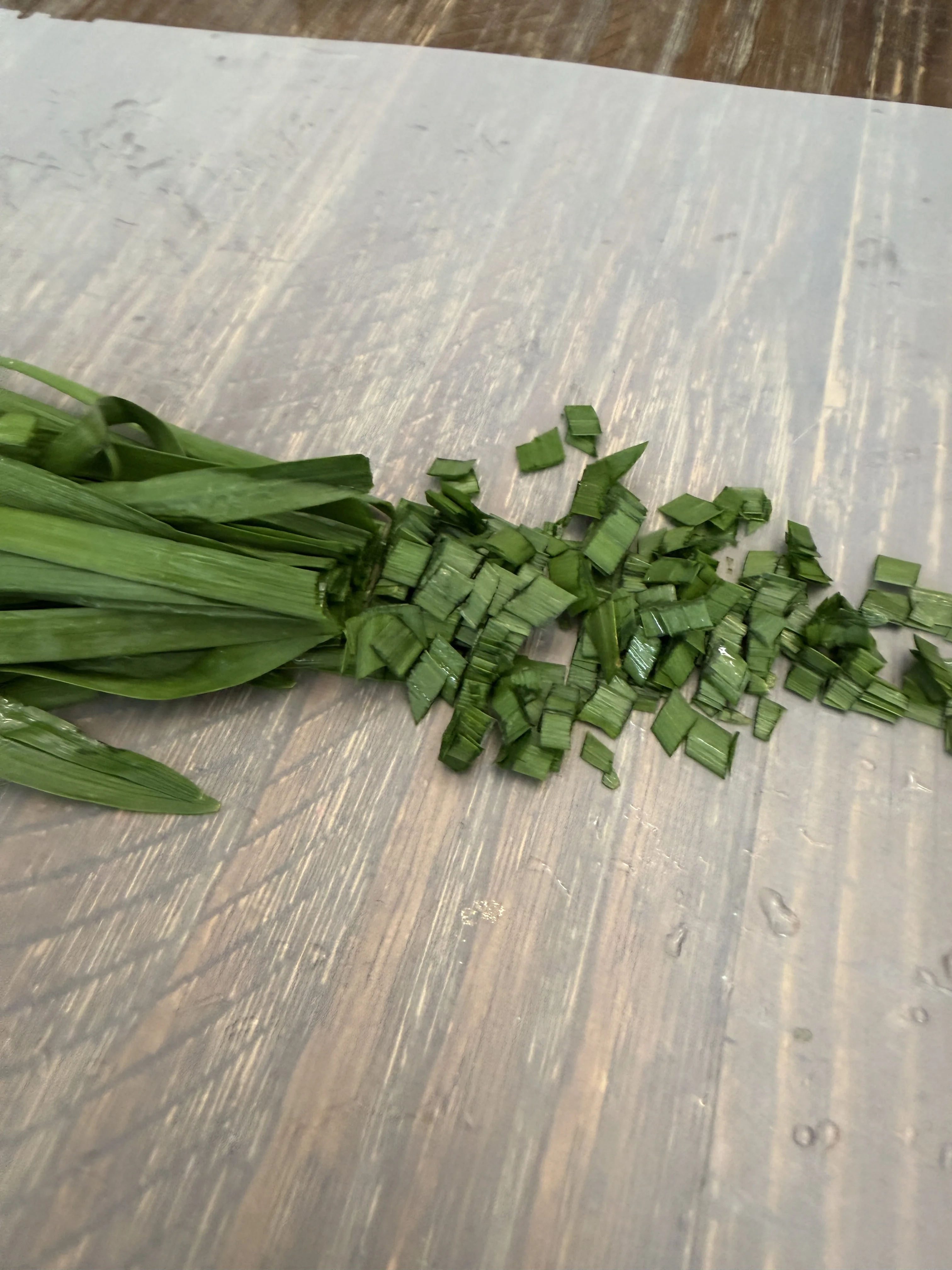 Chinese chives being chopped on a cutting board