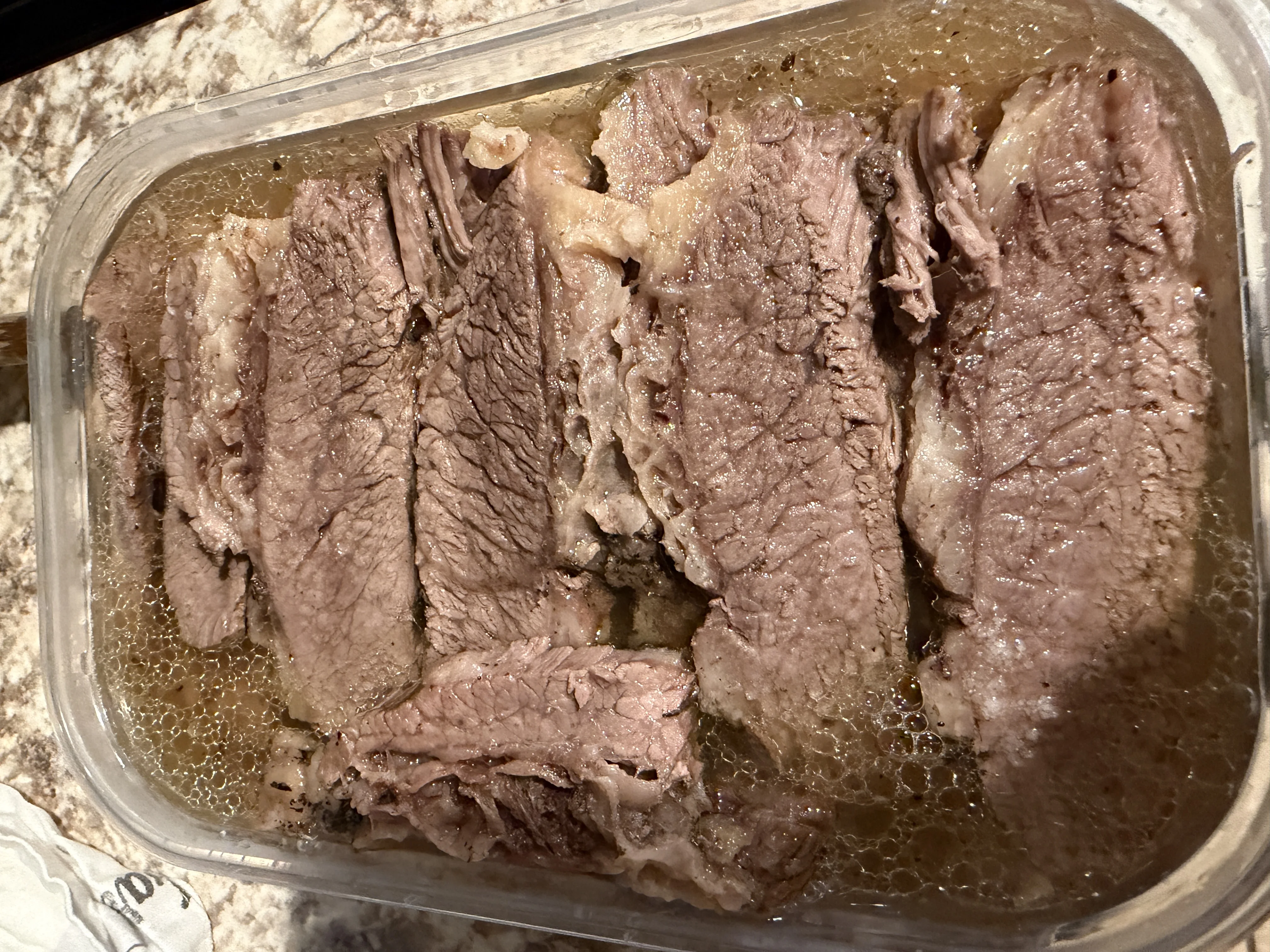 Slow-cooked beef brisket sliced and resting in broth