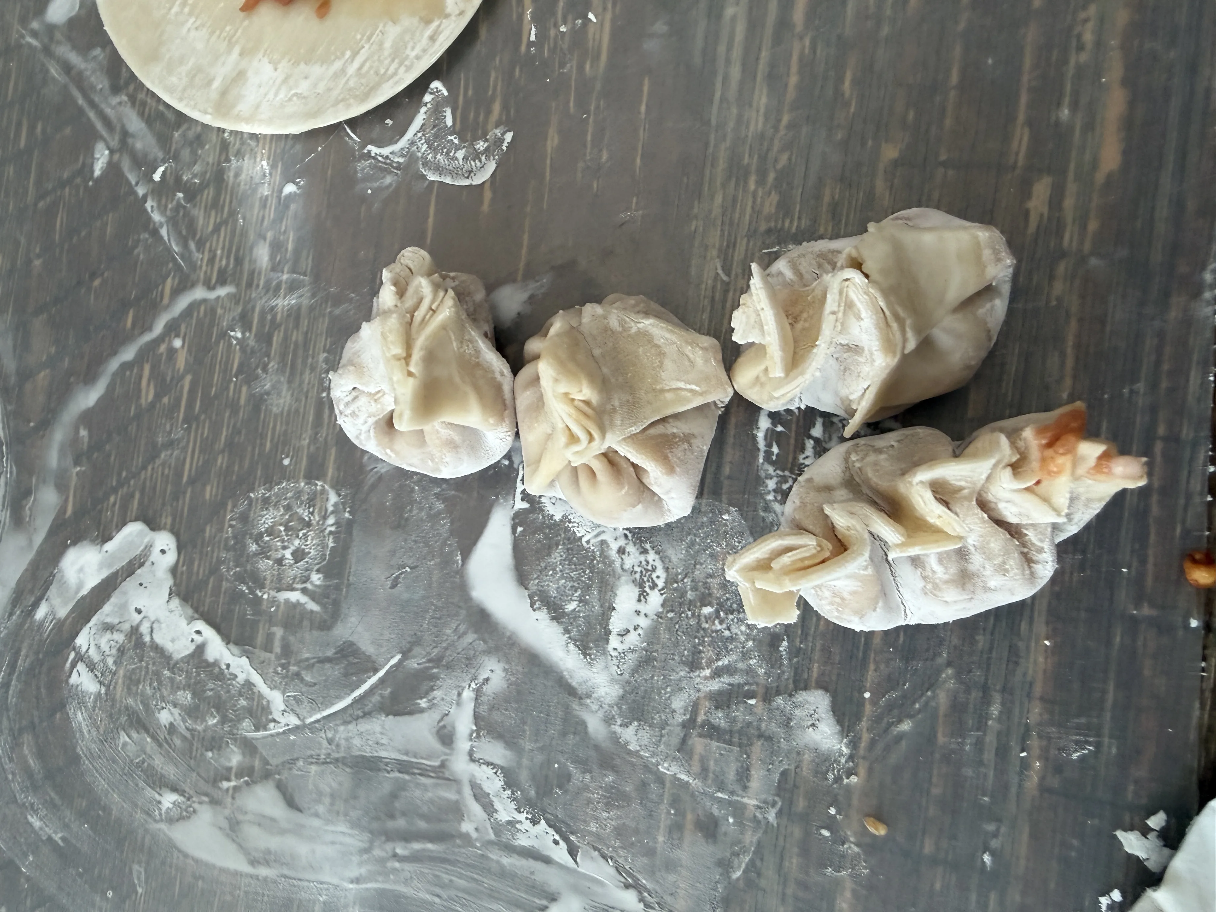Hand-pleated raw dumplings on a floured surface ready for the steamer