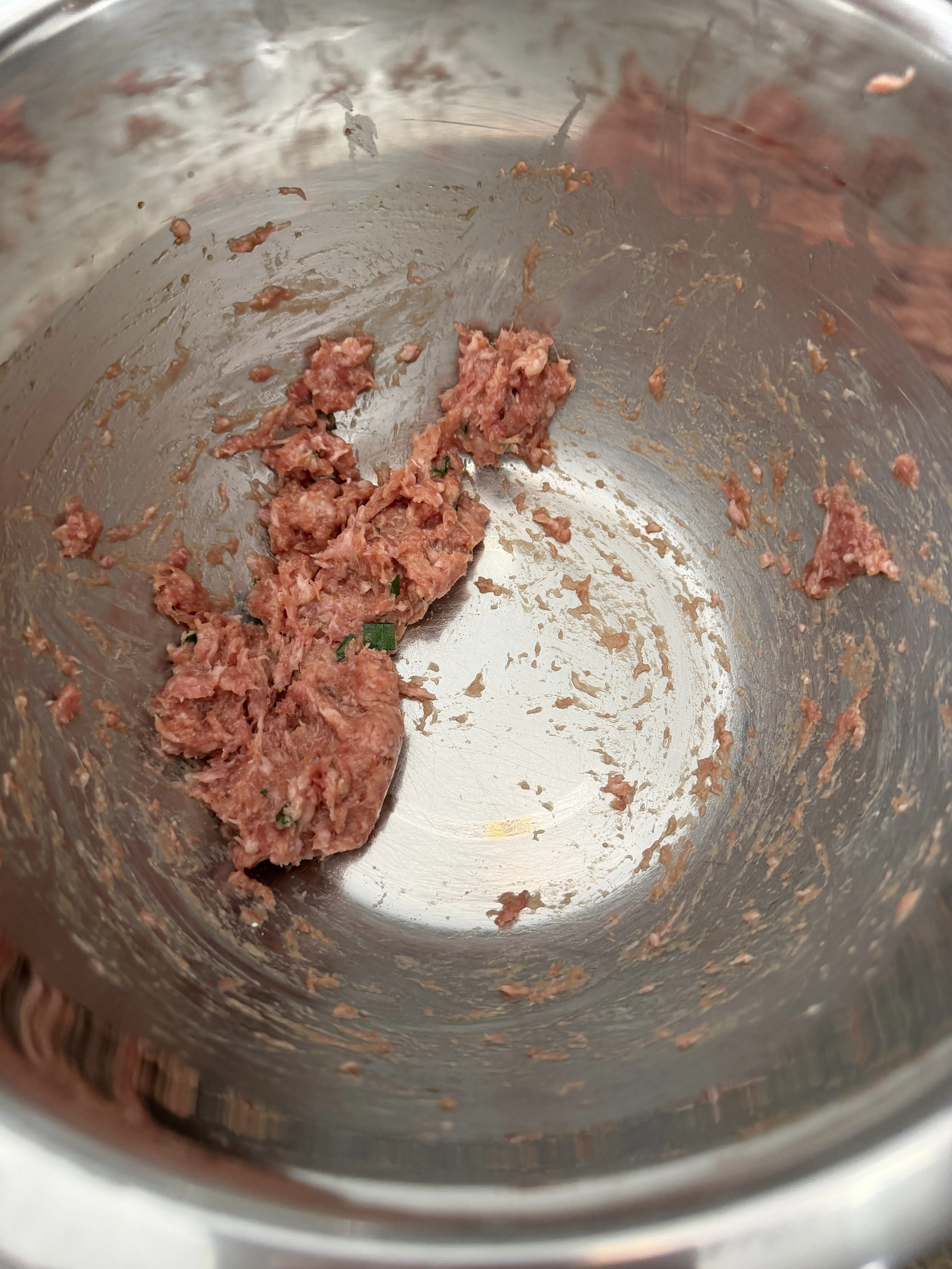 Ground pork being mixed in a stand mixer until sticky and springy