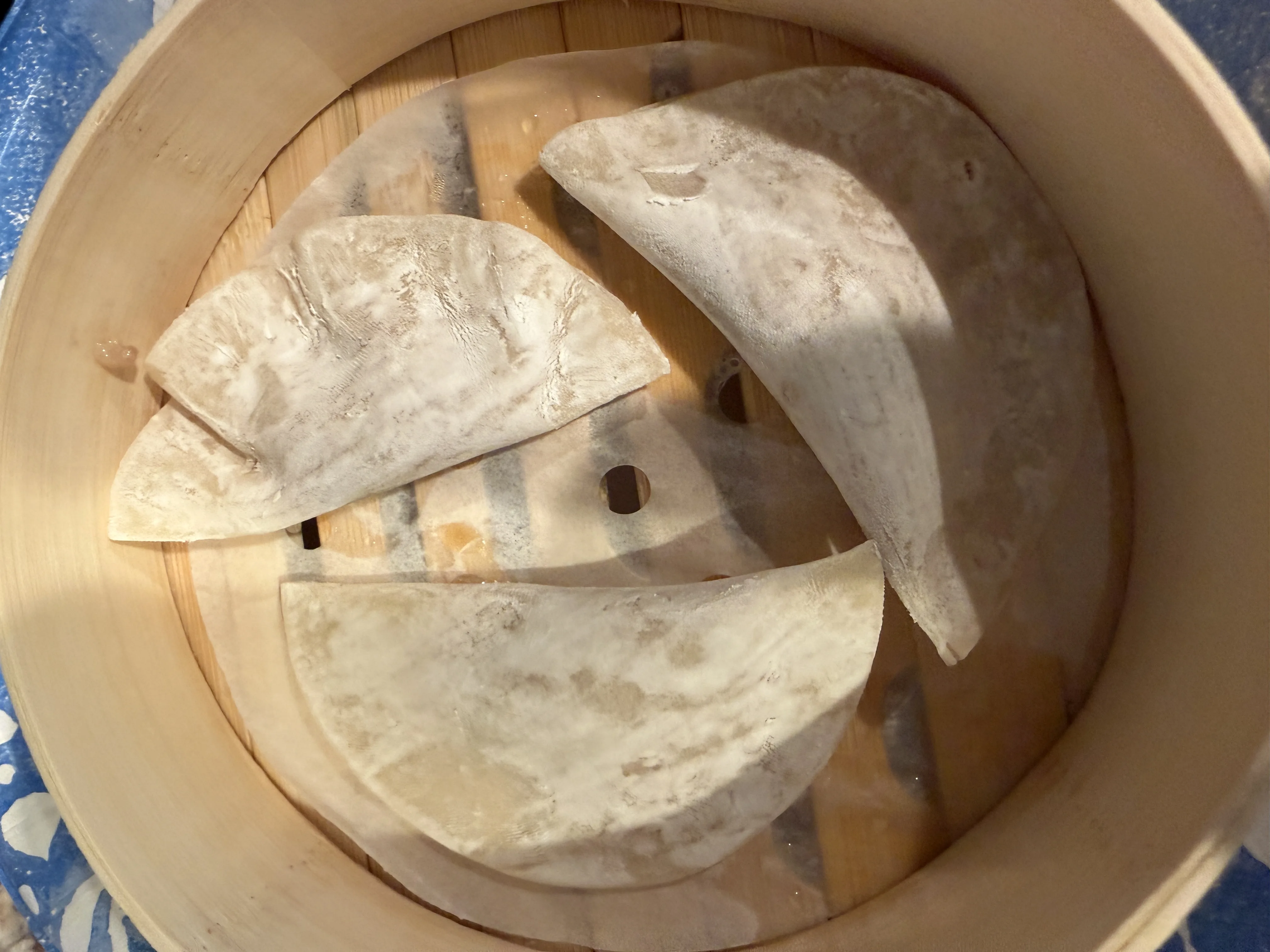Raw half-moon dumplings arranged in a bamboo steamer basket