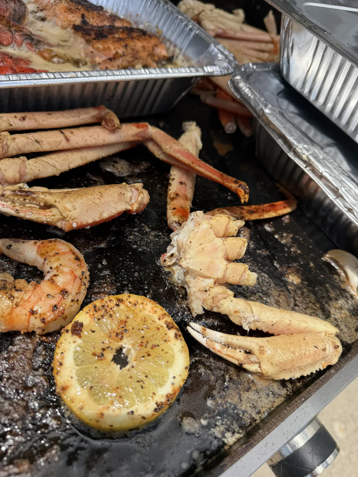 Crab legs and a charred lemon slice on the griddle surface