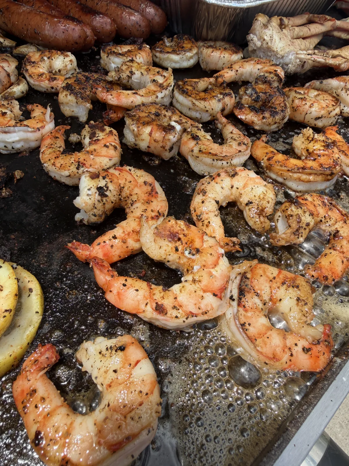 Close-up of shrimp on the griddle showing the coarse black pepper crust from The Gospel rub